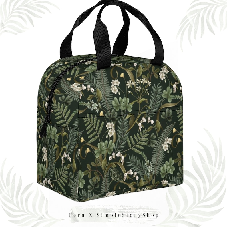 May include: A dark green insulated lunch bag with a botanical pattern of white flowers, ferns, and other foliage. The bag has a black zipper, black handles, and the text "Fern X SimpleStoryShop" at the bottom.