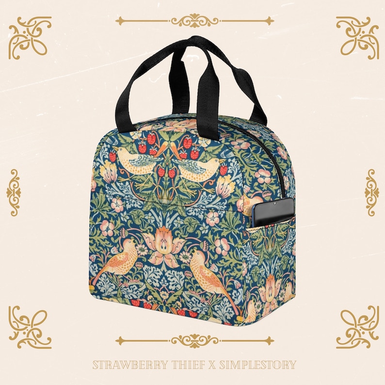 Peut inclure: Un sac &agrave; d&eacute;jeuner bleu et vert avec un motif floral repr&eacute;sentant des oiseaux et des fraises. Le sac a une poign&eacute;e noire et une fermeture &agrave; glissi&egrave;re. Le sac a une petite poche lat&eacute;rale pour un t&eacute;l&eacute;phone. Le sac porte l'inscription "STRAWBERRY THIEF X SIMPLESTORY" en bas.