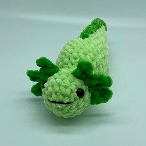 Peut inclure: Jouet en peluche axolotl crochet&eacute; vert avec des yeux noirs. L'axolotl a un petit sourire et de grandes branchies crochet&eacute;es vertes.