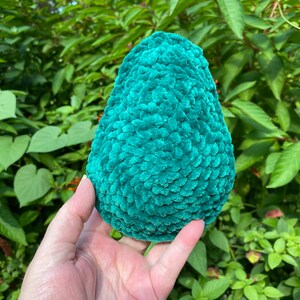 May include: A teal green crocheted avocado shaped plush toy.