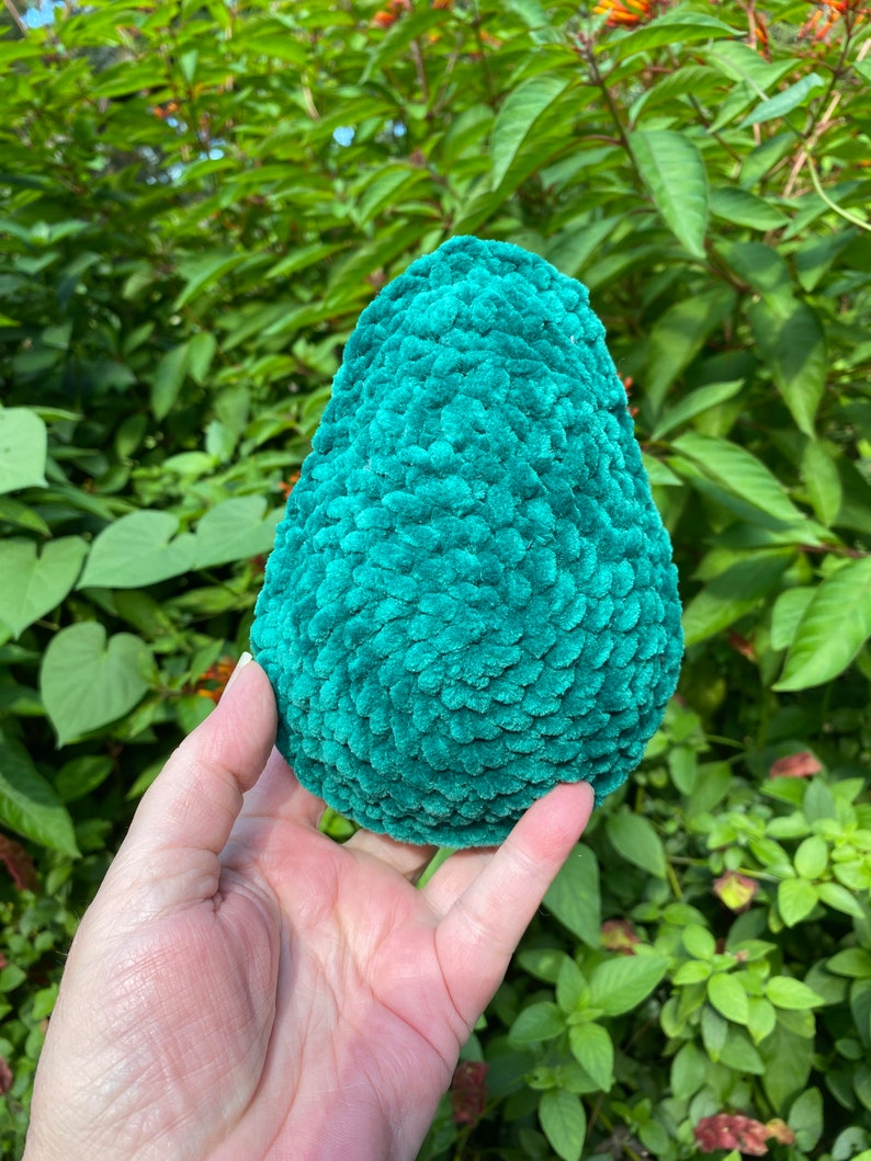 May include: A teal green crocheted avocado shaped plush toy.