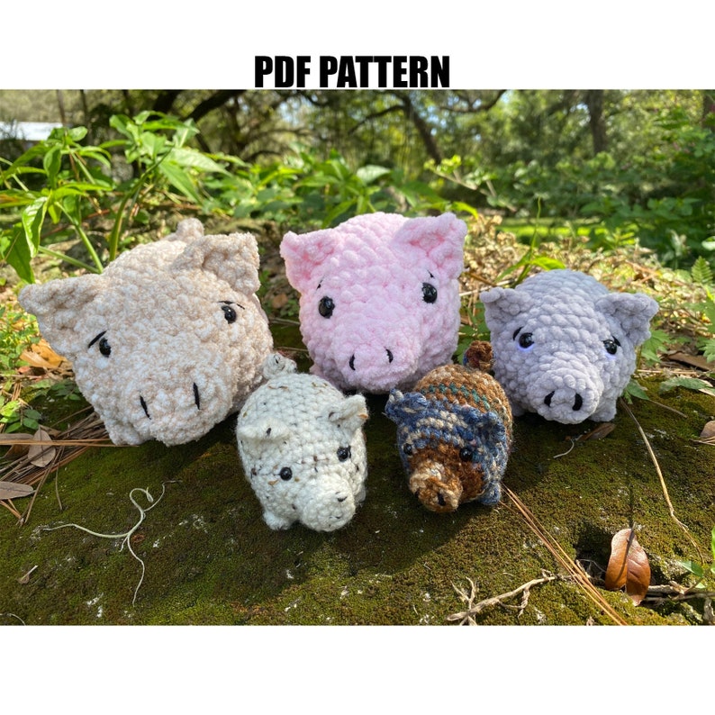 Op de afbeelding: Een verzameling van vijf gehaakte varkensbeeldjes in beige, roze, grijs, wit en bruin met blauwe accenten. De tekst "PDF PATTERN" staat bovenaan. Deze handgemaakte pluche speelgoed wordt getoond op een mosachtig oppervlak.