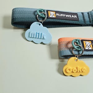 Pu&ograve; includere: Due collari per cani con targhette a forma di nuvola. Una targhetta &egrave; azzurra e dice "milk", l'altra &egrave; gialla e dice "coke". I collari sono verde acqua e arancioni con il logo "Ruffwear".