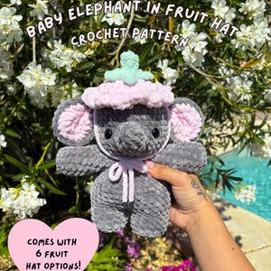 Peut inclure: Un éléphant en crochet gris portant un chapeau de fruits rose et vert. Le texte "BABY ELEPHANT IN FRUIT HAT CROCHET PATTERN" est au-dessus de l'éléphant. Un cœur rose avec le texte "COMES WITH 6 FRUIT HAT OPTIONS!" est en bas à gauche.