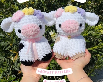 May include: Two crocheted white cow plushies with pink noses and flower crowns. The cow on the left has black and white spots and a pink ribbon. The cow on the right has brown and white spots and a gold bell. The text "FLOWER CROWN COWS CROCHET PATTERN BY AMIBYABI" is on the image.