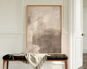 May include: A framed abstract painting with a light brown and gray color scheme. The painting is hanging on a white wall above a wooden bench with a white throw blanket.