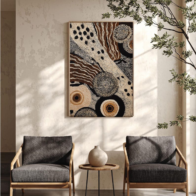 K&ouml;nnte beinhalten: Abstrakter Kunstdruck in einem Holzrahmen. Das Kunstwerk zeigt eine Mischung aus kreisf&ouml;rmigen und linearen Mustern in Beige, Braun und Schwarz. Der Druck wird &uuml;ber zwei grauen Sesseln und einem kleinen Beistelltisch aus Holz mit einer Vase angezeigt.