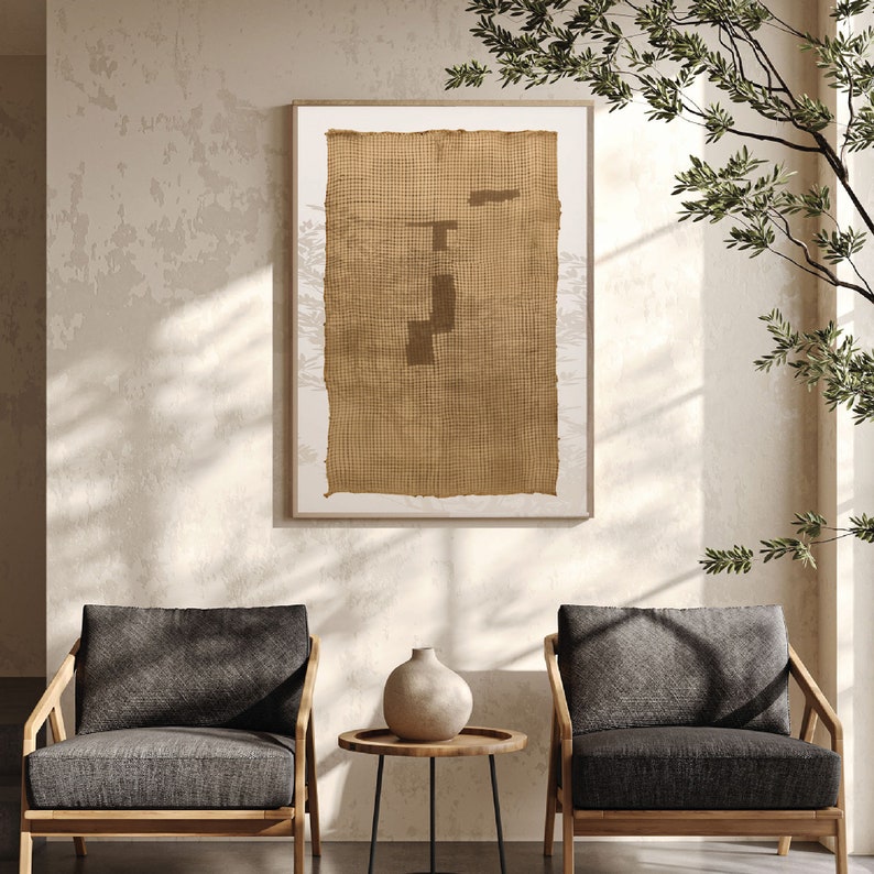 K&ouml;nnte beinhalten: Zwei dunkelgraue Sessel mit Holzrahmen, ein kleiner runder Tisch mit einem schwarzen Metallgestell und eine Keramikvase mit hellbrauner Glasur. Ein gerahmtes Kunstwerk mit einer braunen gewebten Textur h&auml;ngt an der Wand hinter den St&uuml;hlen.