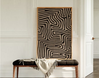 May include: A wooden bench with a beige throw blanket on top. A framed print with a black and beige abstract pattern hangs on the wall behind the bench.
