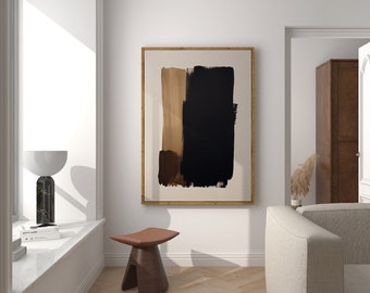 May include: A framed abstract painting with black, brown, and gold brushstrokes on a cream background. The painting is hanging on a white wall in a room with a wooden floor and a white couch.