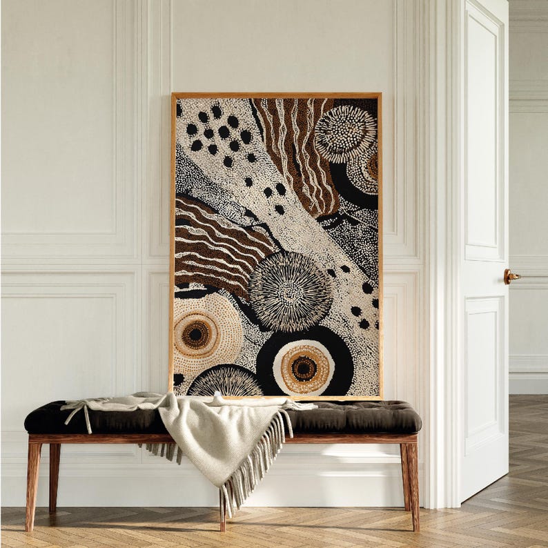 K&ouml;nnte beinhalten: Abstrakter Kunstdruck in einem Holzrahmen. Das Kunstwerk zeigt eine Mischung aus braunen, schwarzen und cremefarbenen Farben mit kreisf&ouml;rmigen und linearen Mustern. Der Druck wird &uuml;ber einer schwarzen Bank mit einer cremefarbenen Decke angezeigt.