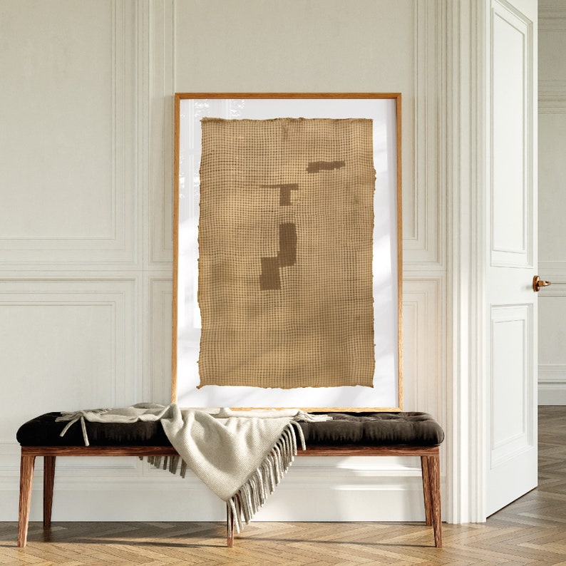 K&ouml;nnte beinhalten: Ein gerahmtes Kunstwerk mit einem braunen gewebten Stoffhintergrund und einem geometrischen Design in einem dunkleren Braunton.