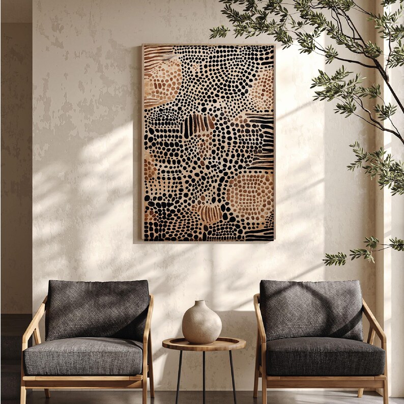 K&ouml;nnte beinhalten: Ein abstrakter Kunstdruck in Schwarz und Braun mit einem geometrischen Muster aus Kreisen und Linien. Der Druck ist in einem hellen Holzrahmen gerahmt und h&auml;ngt an einer beigefarbenen Wand. Zwei graue Sessel mit Holzrahmen stehen vor dem Druck, und ein kleiner runder Tisch mit einer Vase steht zwischen ihnen.