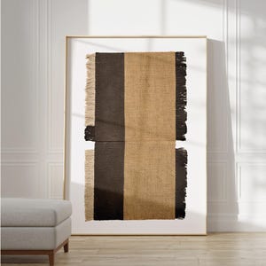 May include: A framed wall hanging with a woven texture. The hanging is made of two different materials, one brown and one beige, with a fringe border.