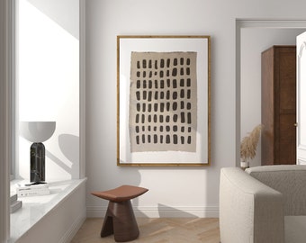 May include: A framed abstract art print featuring a beige background with a pattern of black vertical rectangles. The artwork is displayed in a room with a modern aesthetic, alongside a brown wooden stool and a marble and white lamp.