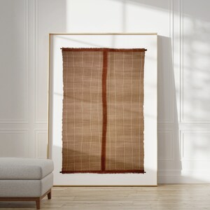 May include: A framed wall tapestry with a brown and white woven pattern and a red border. The tapestry has a fringed edge.