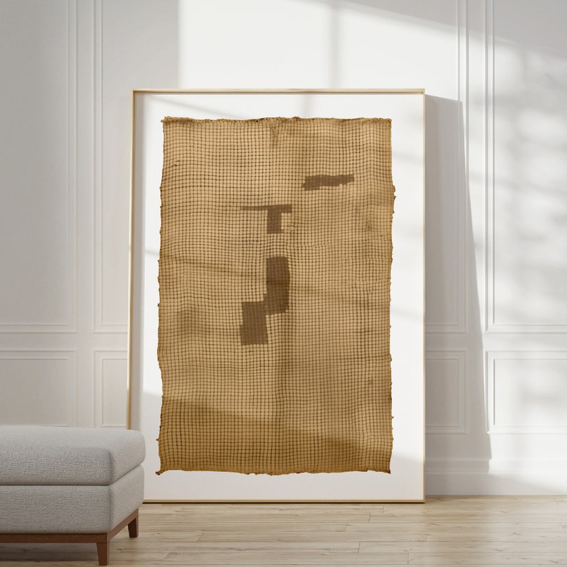 K&ouml;nnte beinhalten: Ein gerahmtes Kunstwerk mit einer gewebten Wandteppich mit einem geometrischen Muster in Braunt&ouml;nen. Der Wandteppich hat eine raue, strukturierte Oberfl&auml;che und wird an einer wei&szlig;en Wand ausgestellt.