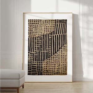 May include: Abstract art print with a tan backdrop and a pattern of black lines and dots. The artwork is framed in a gold-coloured frame and displayed on a white wall. The print has a modern, geometric design.