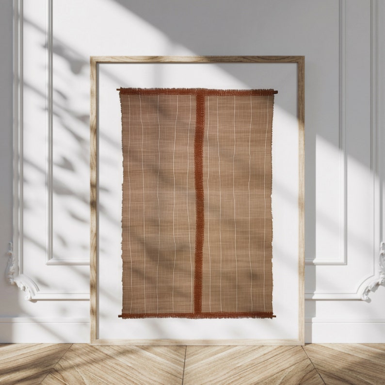 May include: A framed wall hanging with a woven texture in shades of brown and rust. The hanging has a fringe border.