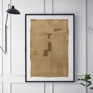 K&ouml;nnte beinhalten: Ein gerahmter abstrakter Kunstdruck mit einer braunen gewebten Textur und einem geometrischen Design in einem dunkleren Braunton.