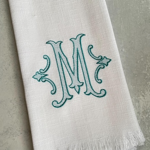 The personalized dish towel features a large initial and two ornaments on either side of the initial. The custom initial is embroidered either in a solid pattern or a striped pattern. makes a great gift.