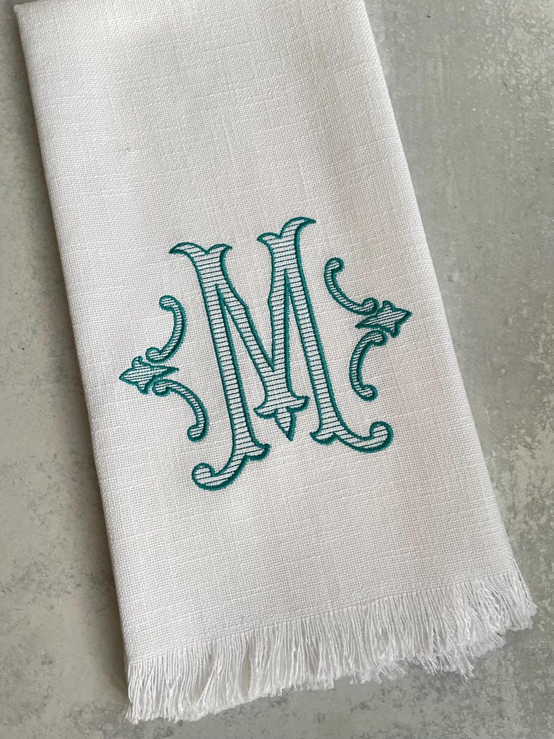 The personalized dish towel features a large initial and two ornaments on either side of the initial. The custom initial is embroidered either in a solid pattern or a striped pattern. makes a great gift.