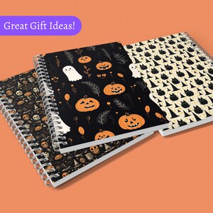 May include: Three spiral bound notebooks with Halloween themed designs. The first notebook has a black background with orange pumpkins, white ghosts, and black leaves. The second notebook has a black background with orange pumpkins and black leaves. The third notebook has a yellow background with black cats wearing witch hats.