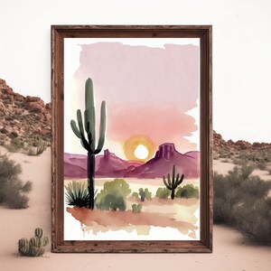 K&ouml;nnte beinhalten: Aquarellmalerei einer W&uuml;stenlandschaft mit einem gro&szlig;en Saguaro-Kaktus im Vordergrund, einer untergehenden Sonne im Hintergrund und violetten Bergen in der Ferne.
