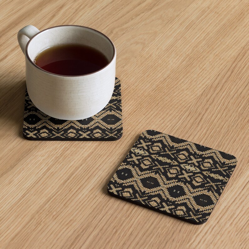 Puede incluir: Dos posavasos cuadrados con un patr&oacute;n geom&eacute;trico negro y beige. Un posavasos sostiene una taza blanca llena de t&eacute;. Los posavasos est&aacute;n sobre una superficie de madera clara. El dise&ntilde;o recuerda a los textiles tribales. Miden aproximadamente 10 cm x 10 cm.