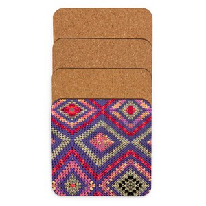 May include: Set of four rectangular coasters. The top coaster features a colorful, geometric pattern in shades of purple, red, pink, and yellow. The bottom of the coasters are made of a natural cork material.