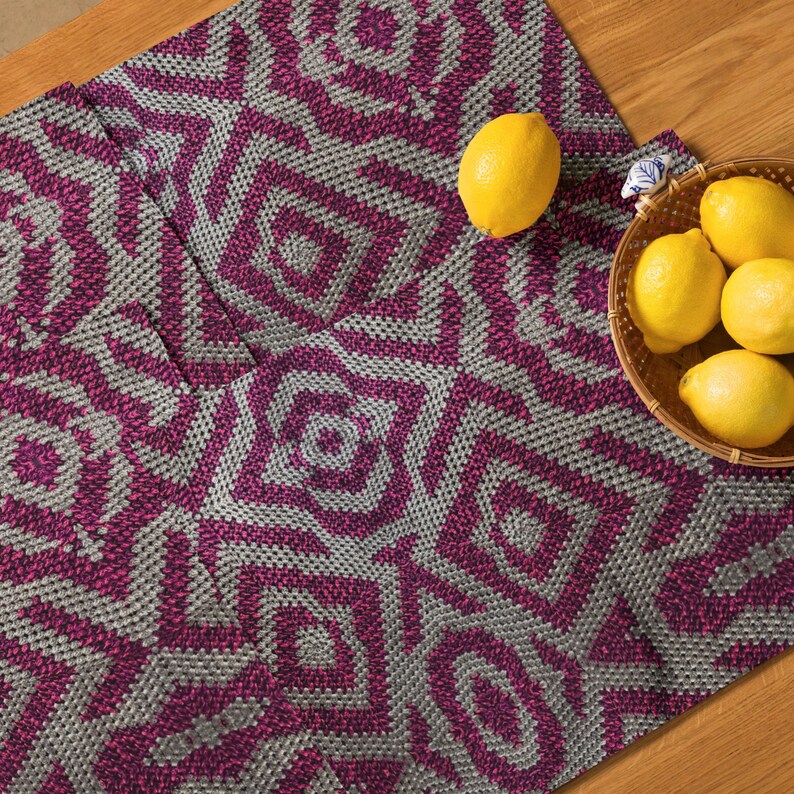 Pode incluir: Dois caminhos de mesa decorativos com um padr&atilde;o geom&eacute;trico em tons de cinza e magenta. Colocados sobre uma superf&iacute;cie de madeira, com uma cesta de lim&otilde;es. Os caminhos de mesa t&ecirc;m uma apar&ecirc;ncia texturizada.