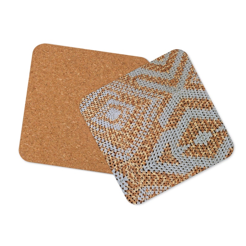 May include: Two square coasters. One is a plain cork coaster. The other has a geometric pattern in shades of grey and brown. The pattern is made of small, repeating squares. The coasters are designed to protect surfaces from heat and moisture.