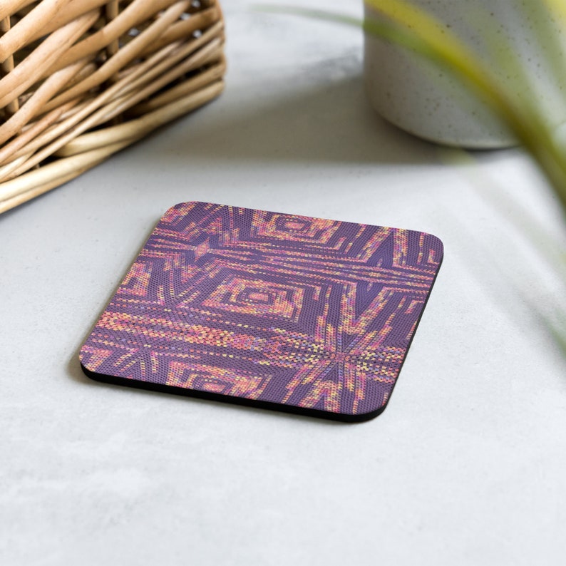 May include: Square coaster featuring a geometric design in purple, pink, and yellow hues. The coaster has a black edge and a textured surface. It is likely made from a durable material, suitable for everyday use.