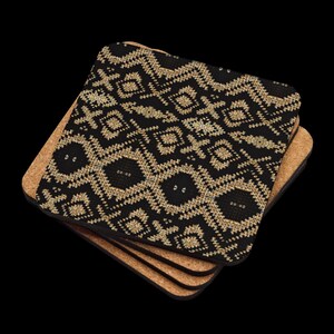 Puede incluir: Un conjunto de cuatro posavasos cuadrados. El posavasos superior presenta un patr&oacute;n geom&eacute;trico dorado repetido sobre un fondo negro. Los posavasos tienen una base de corcho y un borde negro.