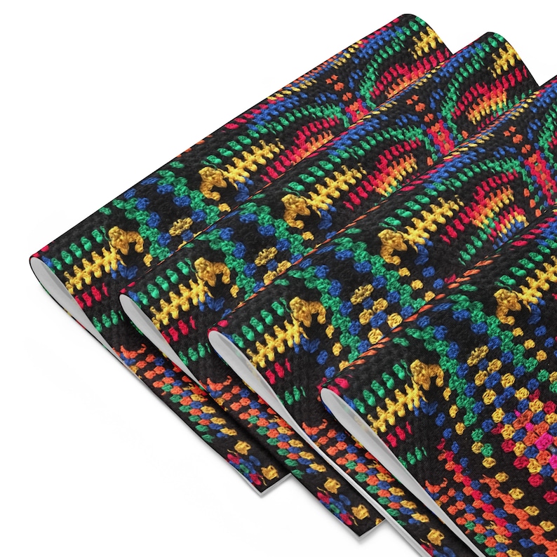May include: A stack of black fabric rolls with a colorful crochet pattern. The pattern features a repeating design of yellow, blue, green, and red stitches. The fabric is rolled up, revealing the white underside.