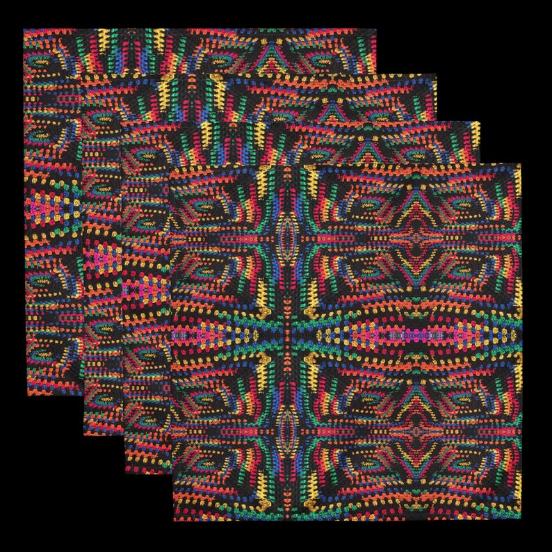 Op de afbeelding: Vier zwarte stoffen servetten met een levendig, herhalend patroon. Het ontwerp toont een caleidoscoop van kleuren, waaronder rood, geel, groen en blauw, waardoor een gestructureerd, geometrisch effect ontstaat. De servetten zijn in lagen gerangschikt.