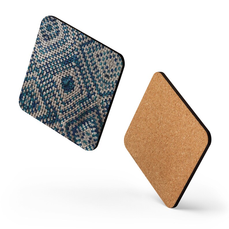 Op de afbeelding: Twee ruitvormige onderzetters. E&eacute;n heeft een gedetailleerd patroon in blauw, turquoise en wit, dat lijkt op een haakontwerp. De andere heeft een natuurlijk kurkoppervlak met een donkerbruine rand.