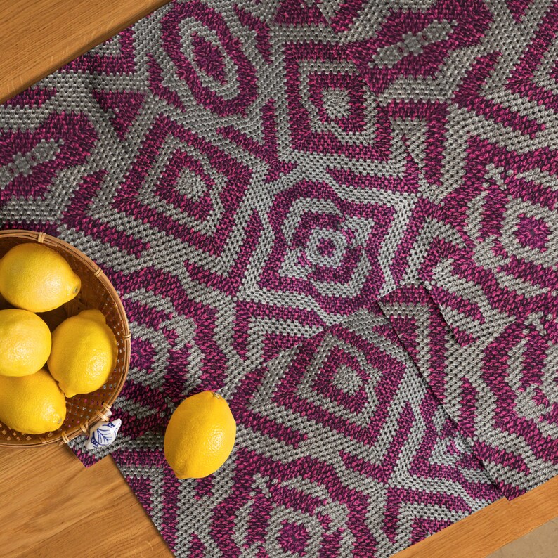 Pode incluir: T&ecirc;xtil tecido com um padr&atilde;o geom&eacute;trico em tons de cinza e magenta. Uma cesta de lim&otilde;es amarelos est&aacute; sobre uma superf&iacute;cie de madeira ao lado do t&ecirc;xtil. O design do t&ecirc;xtil apresenta formas repetidas de diamantes e estrelas.