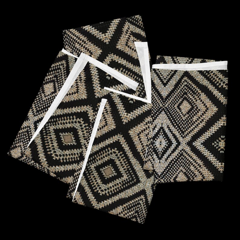 May include: Black and beige geometric patterned fabric with white accents. The fabric features a diamond pattern with a textured appearance. The image shows several pieces of the fabric, possibly cut or folded.