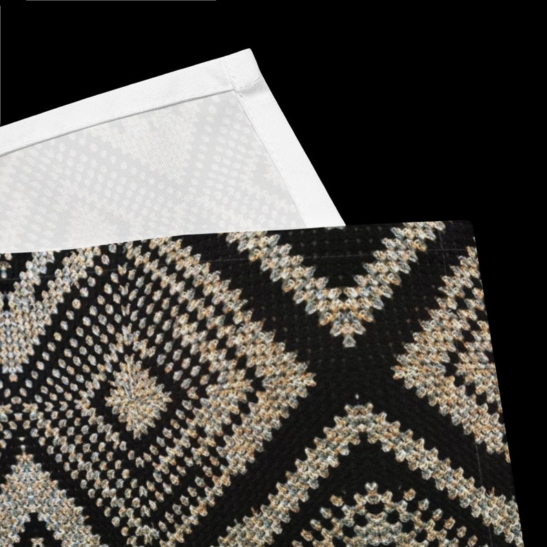 May include: A black and beige patterned textile with a geometric design. The pattern features diamond and zig-zag shapes. A white textile with a dotted pattern is visible in the upper portion of the image.