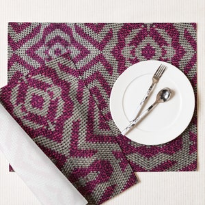 Pode incluir: Uma mesa posta com um prato branco, garfo e colher com um design em preto e branco. O jogo americano e o guardanapo t&ecirc;m um padr&atilde;o geom&eacute;trico em tons de magenta e cinza. O conjunto est&aacute; sobre uma superf&iacute;cie branca.