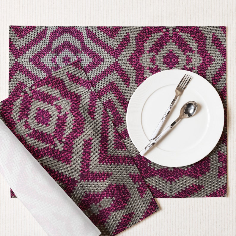 Pode incluir: Uma mesa posta com um prato branco, garfo e colher com um design em preto e branco. O jogo americano e o guardanapo t&ecirc;m um padr&atilde;o geom&eacute;trico em tons de magenta e cinza. O conjunto est&aacute; sobre uma superf&iacute;cie branca.