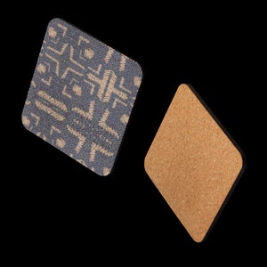 Puede incluir: Dos posavasos en forma de rombo. Uno presenta un patr&oacute;n geom&eacute;trico azul y beige. El otro tiene una superficie de corcho natural. Ambos tienen bordes negros, ofreciendo un aspecto moderno para la decoraci&oacute;n del hogar. Miden unos 10 cm.
