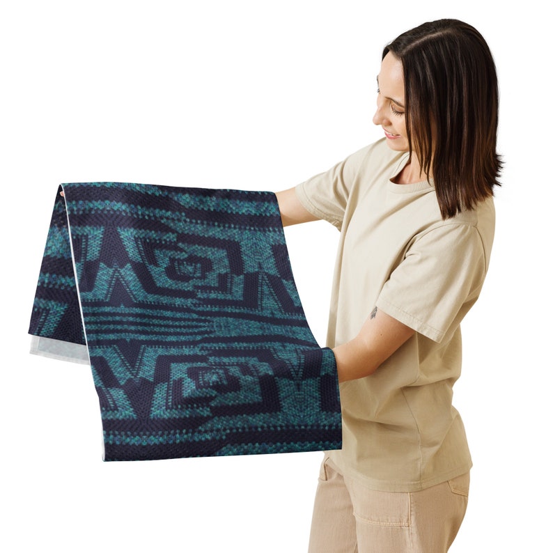 Puede incluir: Un textil doblado con un patr&oacute;n geom&eacute;trico en verde azulado y azul marino. El dise&ntilde;o presenta formas y l&iacute;neas angulares, creando una apariencia texturizada. La tela se sostiene, mostrando los detalles del patr&oacute;n.