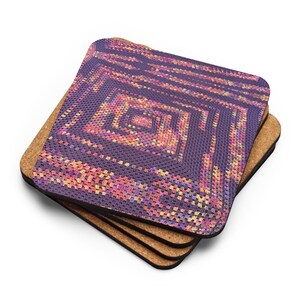 May include: A set of four square coasters with a cork base. Each coaster has a colourful, geometric design on top, in shades of purple, pink, orange, and yellow. The design resembles a crocheted pattern.