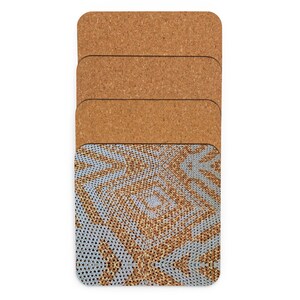 May include: Four rectangular coasters with a cork base. The top coaster has a light blue and gold geometric design. The coasters are made to protect surfaces from drink condensation. Each coaster measures approximately 10 cm x 10 cm.