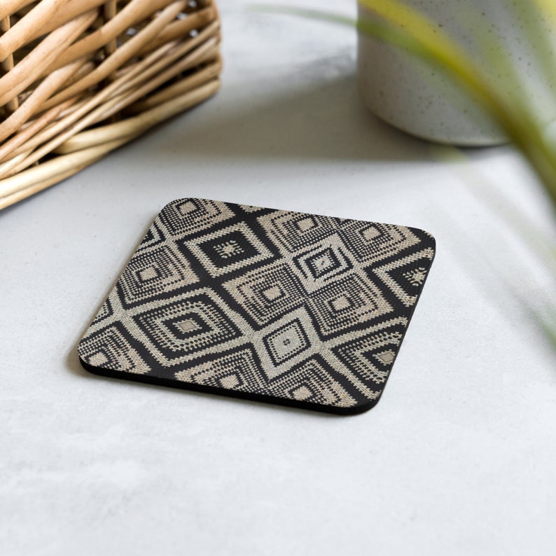 May include: Square coaster with a geometric pattern in black and beige. The design features repeating diamond shapes with a textured appearance. The coaster is made of a durable material and is suitable for use with hot or cold beverages.