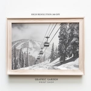 May include: Black and white photograph of a ski lift ascending a snowy mountainside. The lift is full of skiers and snowboarders, and the trees are covered in snow.