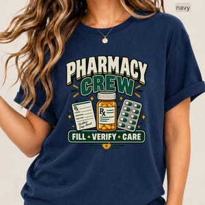 May include: A navy blue t-shirt featuring a graphic with the text PHARMACY CREW, FILL, VERIFY, CARE, an orange pill bottle with an Rx label, a prescription pad, and a blister pack of green and white capsules, with the word navy in the corner.