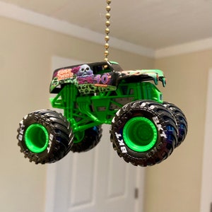 May include: Green monster truck toy with black wheels and "Grave Digger 40th Anniversary" printed on the side. The truck is suspended from a ceiling fan pull chain.